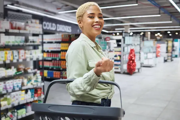 Portrait, basket and woman grocery shopping in supermarket, retail and convenience store for drink. Groceries, market and face of happy African customer in shop for wholesale, sales deal and discount.