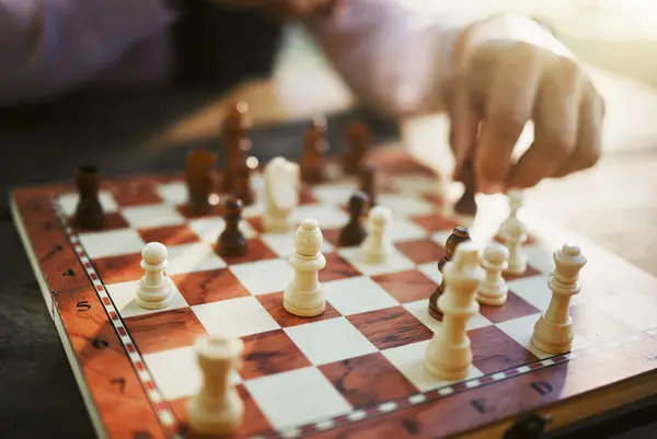 Hands, chess game and board with strategy in competition or challenge, intelligence and closeup of people playing. Thinking, planning and contest outdoor, concentration on boardgame and recreation.