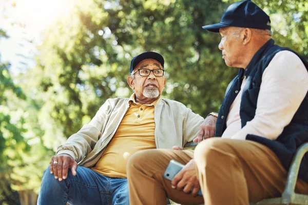 老年朋友 男人和放松在公园的长椅上 在户外用电话交谈和交流 老年人一起坐在花园 交流和严肃的谈天说地 准备在春天退休 — 图库照片