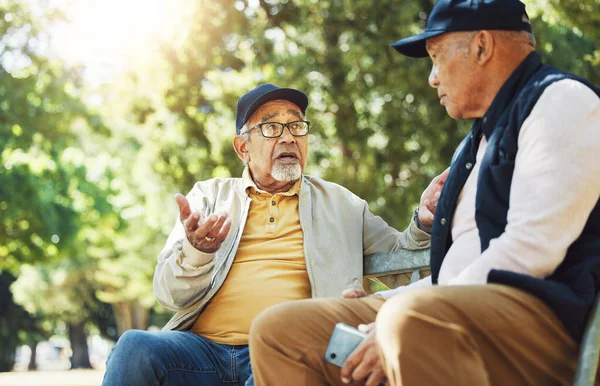 老朋友 男人和在公园长椅上聊天 在户外用电话联系和放松 长者一起坐在花园 沟通及严肃的环境中等待着早上的退休生活 — 图库照片