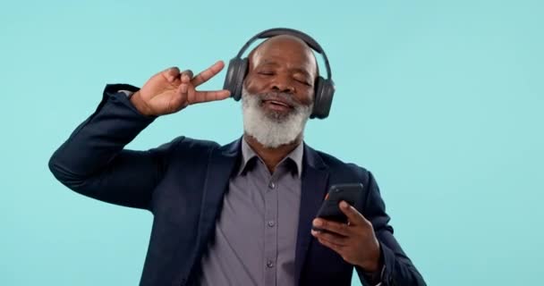 音乐耳机和成熟的黑人男子在蓝色背景的工作室里跳舞 智能手机 收音机和快乐的Ceo听音频 移动到声音与和平的标志 用于在线流媒体 — 图库视频影像