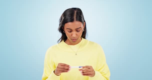 恐ろしい 妊娠テスト 結果とニュースを持つ女性は スタジオブルーの背景で孤立した恐怖や心配を待っています 医学的および神経質な妊娠中の母性ストレスについて考える — ストック動画
