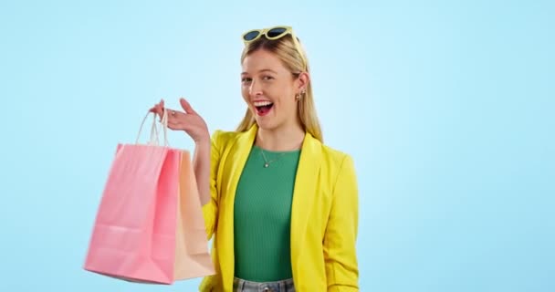 快乐的女人 购物袋和时尚打折 销售或商业庆典 成功或在蓝色背景下获胜 工作室里兴奋的顾客或零售礼品 礼品或服装的获奖者的脸 — 图库视频影像