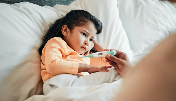 Girl child, thermometer for fever and sick in bed, health and wellness, parent monitor temperature at home. Headache, illness and young kid with the flu virus, medical help and support in bed.