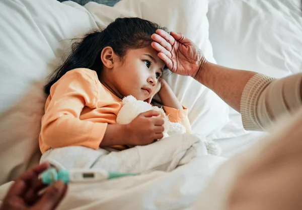 Girl child, check for fever and sick in bed with thermometer, health and wellness, parent monitor temperature at home. Headache, illness and young kid with the flu, medical help and support in bed.