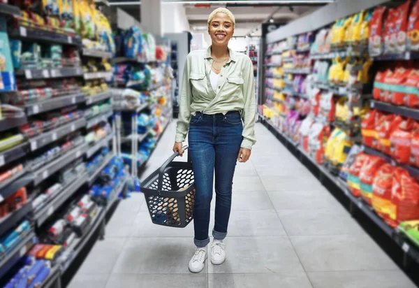 Portrait, basket and happy woman grocery shopping in retail, supermarket and convenience store for food. Groceries, market and African customer smile in shop for wholesale, sales deal and discount