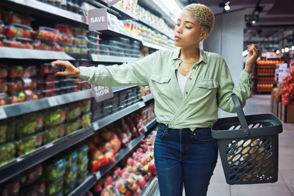 Woman, grocery shopping and fruits choice, discount and sale or wholesale promotion for healthy food and basket. African customer with strawberry package in retail, convenience store or supermarket.