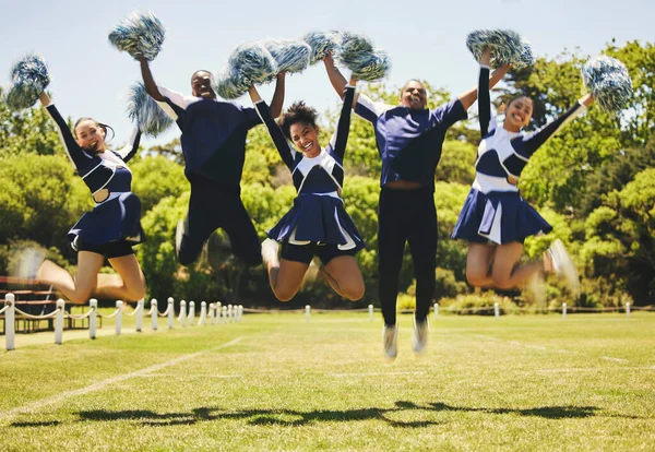 Cheerleader team portrait, people and jump for performance on field outdoor in training, celebration or exercise. Happy, cheerleading group and energy for support at event, sport competition and blur.