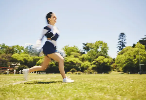 Fitness, cheerleader and woman running on a field for match motivation, energy or performance. Sports, runner and cheerleading female with freedom at a park for game training, practice or competition.