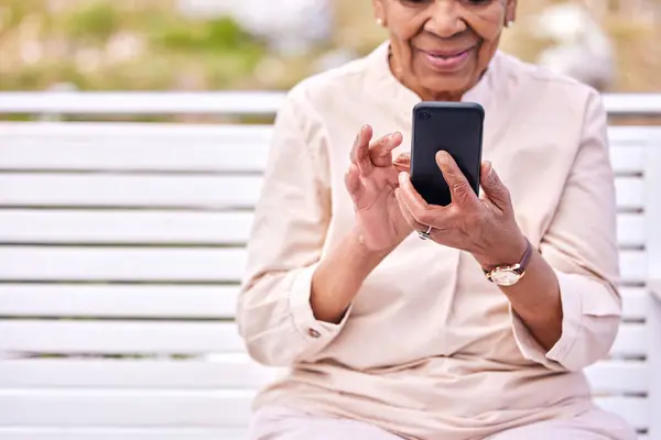 ガーデンベンチに座っているソーシャルメディアスクロールとテキスト付きのシニア女性 高齢女性 モバイルネットワーキング インターネットアプリ オンラインリーディングから笑顔 — ストック写真
