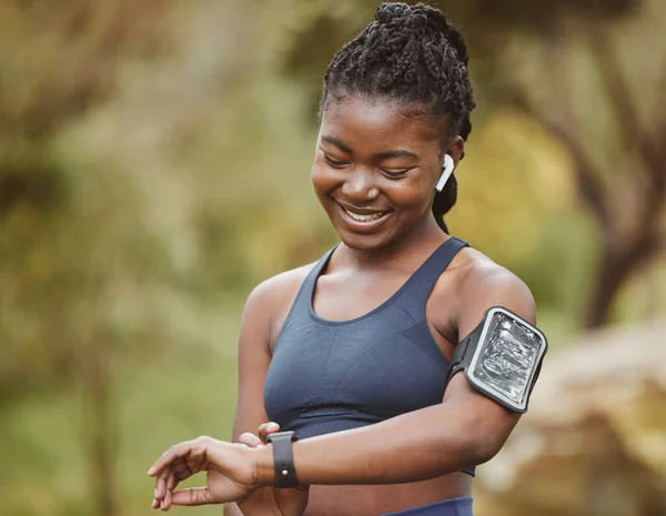 Fitness, smart watch and woman tracking performance on outdoor exercise, workout or training in a forest. Heart rate, wellness and young black person ready and listening to music, audio or podcast.