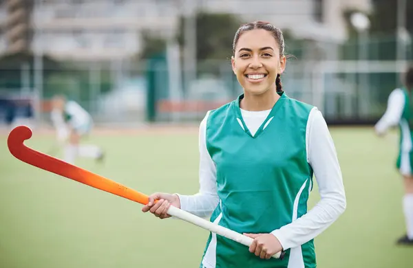 Female, person and happy for hockey with stick in hand on field for training in portrait. Girl, hold and smile with confidence for sports with pose, stand and equipment for match, game or fitness.