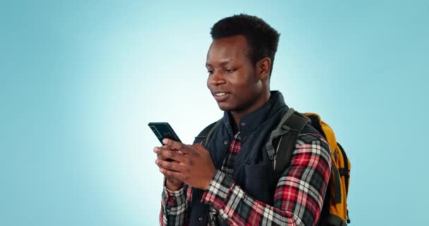 搜索和旅行与黑色男子与背包在工作室旅行 远足或文字蓝色背景 具有位置或社交媒体传播的智能手机 应用程序和快乐的非洲人 — 图库视频影像