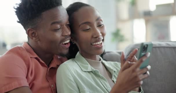 オンライン接続 ソーシャルメディア インターネットの通知のための自宅のカップル ソファー 幸せな黒人男性と女性 モバイルネットワークと一緒に情報 コミュニケーション 幸福を検索する — ストック動画