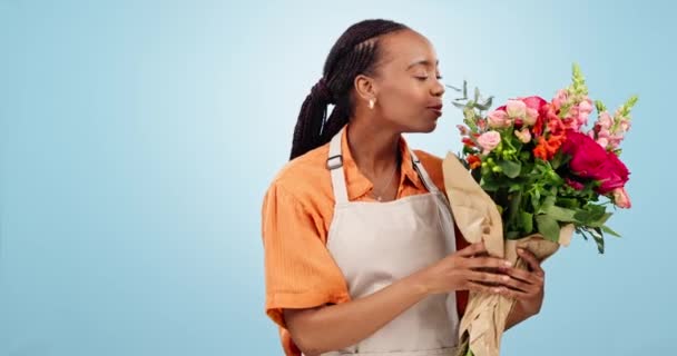 笑一笑 花匠和黑人女人在工作室里闻到了花朵的香味 被蓝色的背景造型隔离了 小商铺里的肖像 花束和企业家嗅到植物的花香 笑着说笑着 — 图库视频影像
