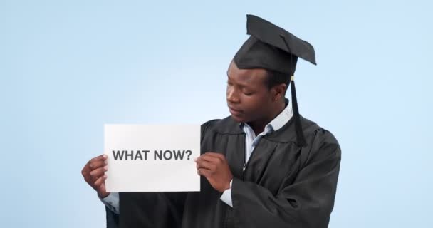 スタジオでサインを持った卒業生と黒人の男性は 卒業後のキャリア そして計画を混乱させた 青い背景のポスターに疑問を持つ学生の大学 肖像画 — ストック動画
