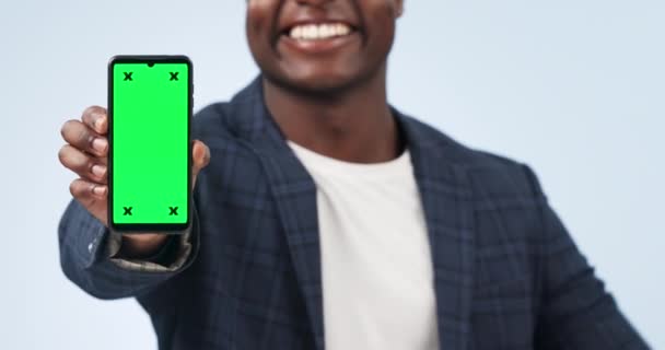 ハッピーマン スタジオの背景に対して広告やマーケティングで緑色の画面を指す 追跡マーカーでモバイルスマートフォンアプリ ディスプレイ モックアップを表示するビジネスマンのクローズアップ — ストック動画