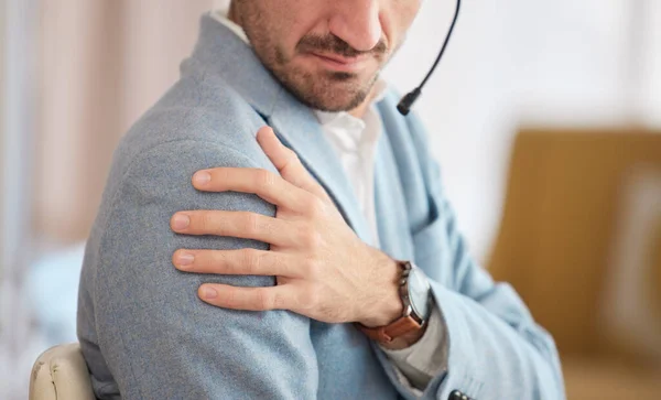 Call center, businessman and shoulder pain in office from stress, joint ache or burnout with customer support. Risk, man and employee in telemarketing with muscle injury, osteoporosis or anxiety.