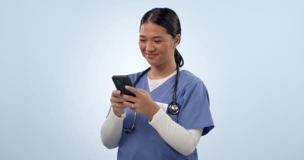 スタジオの背景に対するコミュニケーションやソーシャルメディアのためのハッピーアジアの女性 医療従事者 看護師は 研究やネットワーキングのためのモバイルスマートフォンで笑います — ストック動画