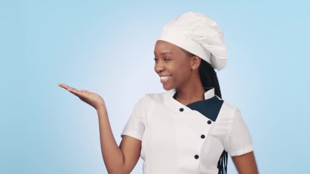 快乐的黑人女人和指手心的手势烹饪宣传 餐厅服务广告或产品放置 食品工业肖像 模拟演播室空间和蓝色背景的烘培者广告 — 图库视频影像