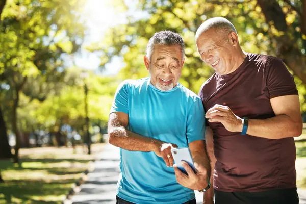 Social media, men and a phone in a park for fitness, training results and conversation about an app. Happy, communication and senior friends with a mobile to monitor health after exercise or running.
