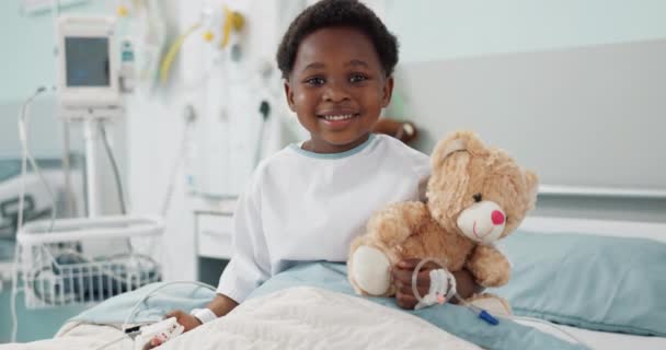 非洲男孩 医院和泰迪熊躺在床上 脸上带着笑容或休息 以便从手术 治疗或健康中恢复过来 耐心的孩子 快乐的肖像画来放松 抱着和诊所一起照看玩具 — 图库视频影像