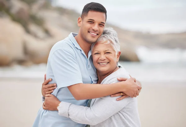 Man, senior mom or portrait at beach on mothers day for bond, support or love with smile, care or pride. Hug, retirement or mature mother with a happy son at sea together on family holiday vacation.