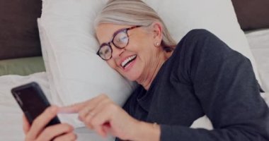 Cep telefonu, kahkaha ve yatakta yaşlı bir kadın internette komik, komik ya da komedi videoları izliyor. Happy, teknoloji ve emeklilik parşömenindeki yaşlı kadın evde telefonla sosyal medyada