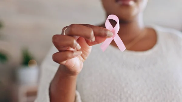 Hand, person with pink ribbon and breast cancer awareness, health and support with care. Healthcare, campaign with symbol or icon, disease prevention with closeup of bow and wellness with sign.