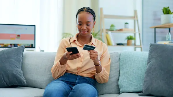 Black woman, phone and credit card on sofa for payment, online shopping or fintech at home. Happy African female person in relax with debit or mobile smartphone for transaction, bank app or ecommerce.