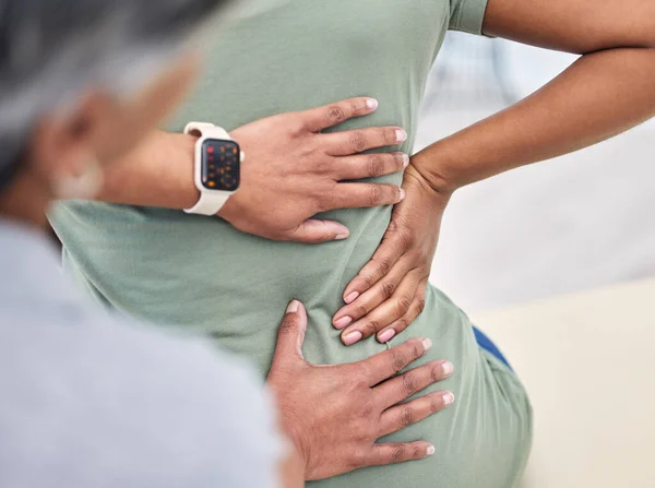Back pain, hands in physical therapy and chiropractor with patient, spine injury and healthcare, help and people at clinic. Physiotherapy, massage and anatomy with body, support and trust in health.