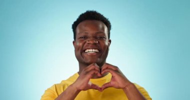Mutlu, yüzü ve kalbi olan siyah bir adam mavi bir arka planda ilgi, destek ve flört için. Gülümse, göz kırp ve Afrikalı bir insanın portresi Sevgi, şefkat ve minnettarlık için bir jestle.