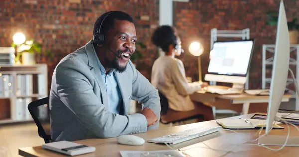 African man, call center and happy by computer, smile and excited for tech support, contact us or email. Consultant, crm or agent in night, telemarketing or customer service with smile in workplace.
