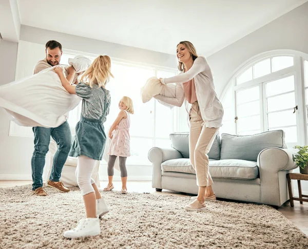 Happy family, pillow fight and playing in living room together for fun holiday, weekend or bonding at home. Mother, father and children smile with cushion game, play or free time for summer break.