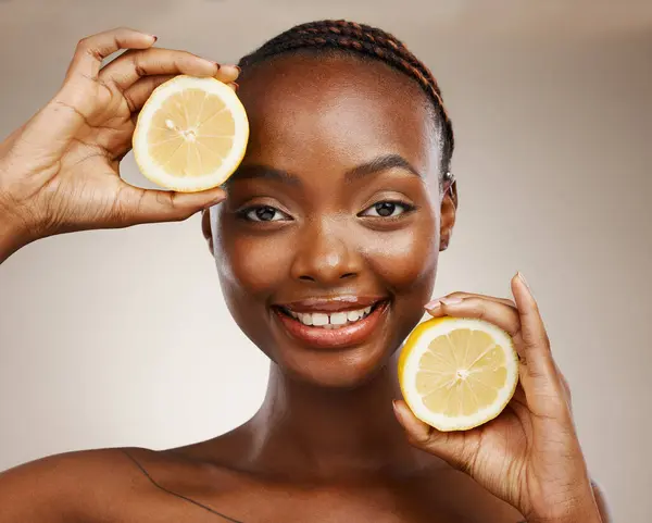 Black woman, lemon fruits and portrait of beauty in studio for vitamin c, vegan cosmetics and facial on brown background. Face of happy model, citrus nutrition and sustainability for natural skincare.