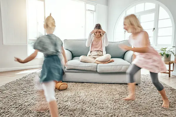 Mother, children and running in living room chaos with headache in stress on sofa at crazy or busy home. Frustrated single parent in burnout with ADHD or hyperactive kids or siblings playing in house.