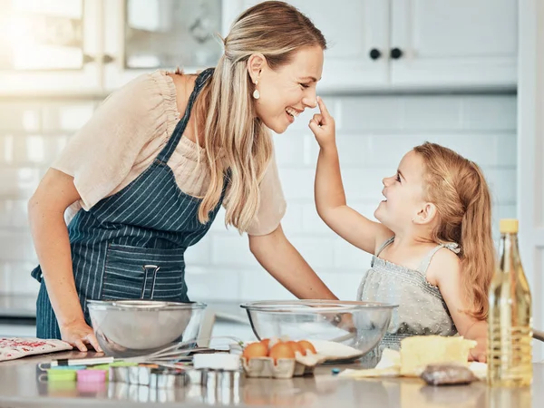Happy mother in kitchen, bake together with child and flour, playing and learning with woman. Love, mom and girl kid with help baking cookies in home with care, support and teaching at playful lunch