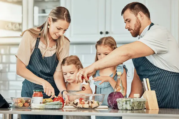 Happy family in kitchen, cooking together with kids and teaching, learning and nutrition with parents. Mom, dad and girl children help making healthy food in home with care, support and love at lunch.