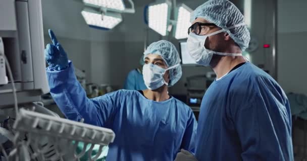 医疗队 人员和医生在手术室里谈话 策略和指点手术的屏幕 男男女女在医疗保健方面的擦洗 在剧场配备有X光监测器 — 图库视频影像