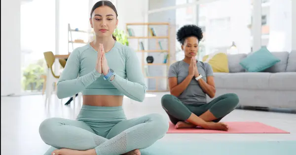 Women friends, yoga and meditation with namaste on floor, peace or zen fitness in home living room. Girl, personal trainer and exercise for health, workout or prayer hands in lounge for mindfulness.