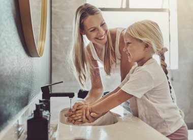 Banyo, anne ve çocuk el yıkama suyu, sabun ve sağlıklı hijyeni birlikte öğreniyorlar. Parmaklarda kir, mikrop ya da bakteri temizleme, anne ve kız sabah sağlığı, yardım ve bakım için evdeler.