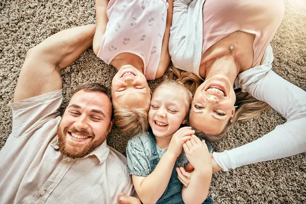 stock image Smile, portrait and kids with parents in the living room bonding and relaxing together at home. Happy, love and girl children laying with mother and father from Australia on floor in lounge at house