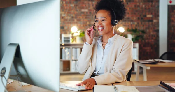 Woman, call center and computer in night, office and talking for telemarketing, voip mic or contact us. African consultant, crm and tech support agent for customer care, ideas or advice at help desk.