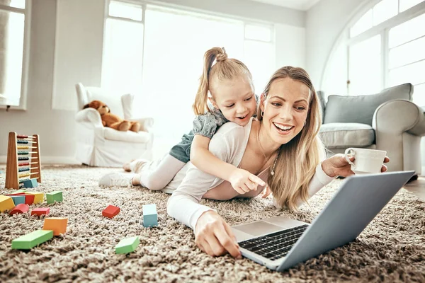 Mother, child and laptop for home games, e learning and happy video streaming or education on carpet in living room. Mom, family and girl play on floor and computer for kids website or online school.