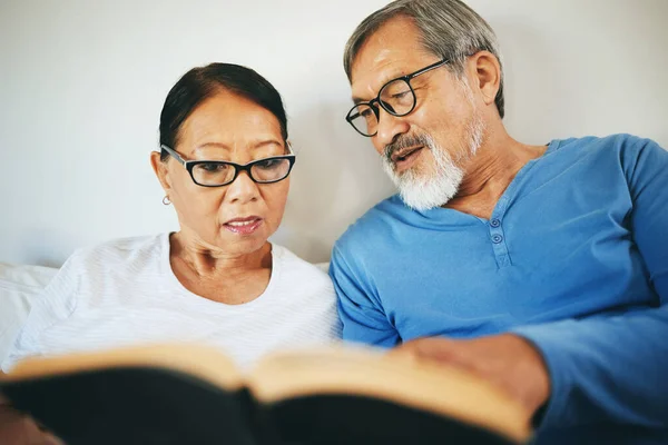 Bible, home or senior couple reading book for prayer, support or hope in bed to worship together. Education, Asian man or mature woman learning or studying God for grace in religion with love or care.