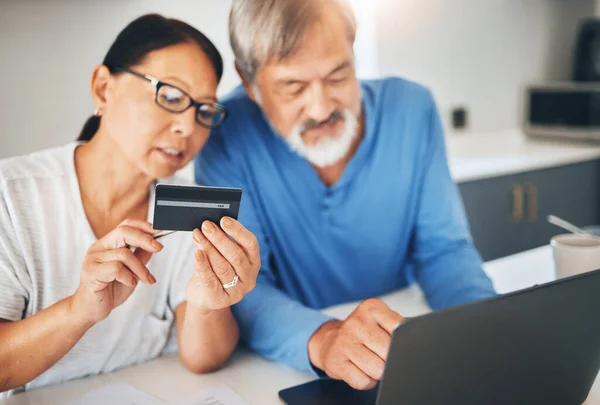 Mature couple, credit card and laptop for home online shopping, loan application or financial management in kitchen. Man and woman with computer for internet banking, security numbers or registration.