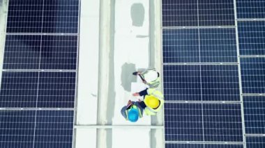 Tepede, güneş enerjisi ve bir binanın çatısına panel teknolojisi yerleştirmek için bir bakım ekibi var. İnşaat, müteahhit ve yenilenebilir elektrik. İnsanlar sürdürülebilirlik projesi üzerinde çalışıyor..