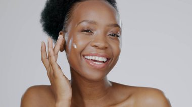 Portrait, cream and face of black woman in studio for beauty, dermatology and aesthetic makeup on grey background. Happy model, sunscreen lotion and facial cosmetics for clean skincare, glow or shine. clipart