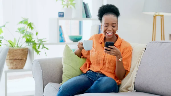 Coffee, woman and laugh with phone on sofa, reading social media post and mobile chat at home. Happy african person drinking tea, scroll multimedia connection and funny meme online with smartphone.