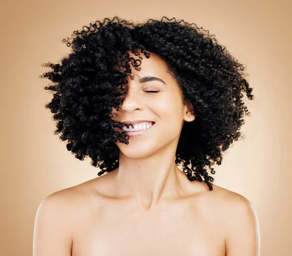 Happy woman, curly or afro hair wind on fun studio background for healthy hairstyle growth, texture or frizz treatment. African beauty model, shake energy and change by shampoo transformation results.